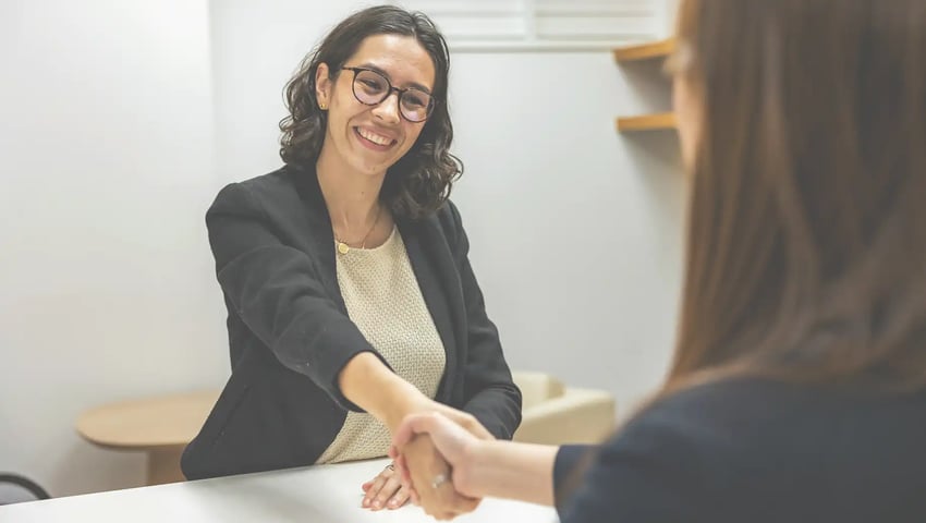 Woman shaking hands with a recruiting manager during the hiring process for insurance agents